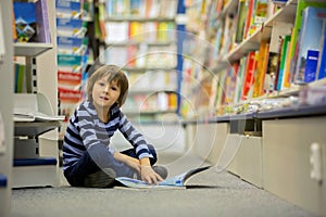 Adorable little child, boy, sitting in a book store