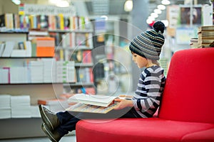Adorable little child, boy, sitting in a book store