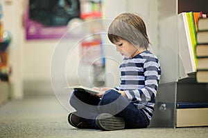 Adorable little child, boy, sitting in a book store