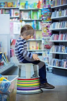Adorable little child, boy, sitting in a book store