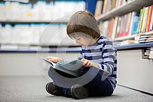 Adorable little child, boy, sitting in a book store