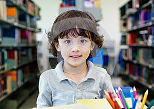 Adorable little child, boy, sitting in a Library, reading books