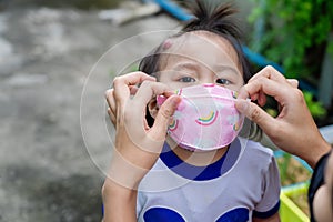 Adorable little child girl with big capillary strawberry hemangiomas red birthmark on head refuses to wear medical face mask