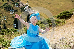 Adorable little child girl with bubble blower on grass on meadow. Summer green nature background