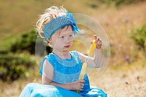 Adorable little child girl with bubble blower on grass on meadow. Summer green nature .