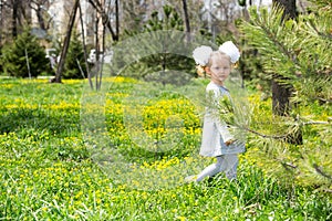 Adorable little child girl on grass on meadow. Summer green nature background.