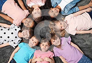 Adorable little children lying on floor together indoors. Kindergarten playtime activities