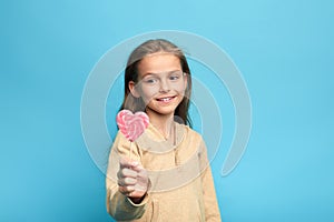Adorable little cute girl holding pink lollipop isolated over blue background