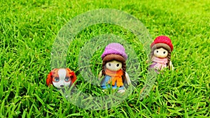 Adorable little dog and beautiful girl dolls sitting on the green grass garden look lovely and cute.