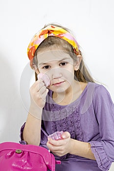 Adorable little girl applying make-up with powder