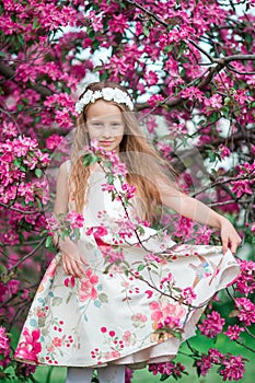 Adorable little girl in beautiful blooming apple garden outdoors