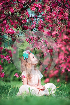 Adorable little girl in beautiful blooming apple garden outdoors