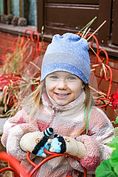 Adorable little girl with a big smile wearing a cute blue hat and colorful jacket