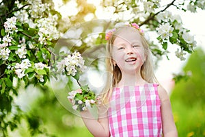 Adorable little girl in blooming apple tree garden on beautiful spring day