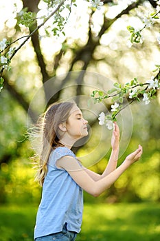 Adorable little girl in blooming apple tree garden on beautiful spring day