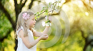 Adorable little girl in blooming apple tree garden on beautiful spring day