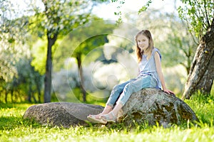 Adorable little girl in blooming apple tree garden on beautiful spring day