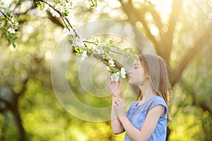 Adorable little girl in blooming apple tree garden on beautiful spring day