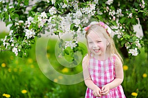 Adorable little girl in blooming apple tree garden on beautiful spring day