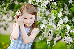 Adorable little girl in blooming apple tree garden on beautiful spring day