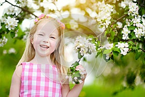 Adorable little girl in blooming apple tree garden on beautiful spring day