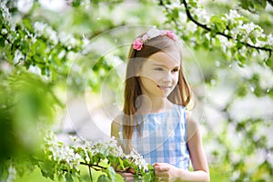 Adorable little girl in blooming apple tree garden on beautiful spring day