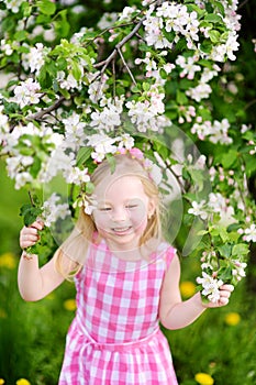 Adorable little girl in blooming apple tree garden on beautiful spring day