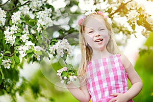 Adorable little girl in blooming apple tree garden on beautiful spring day