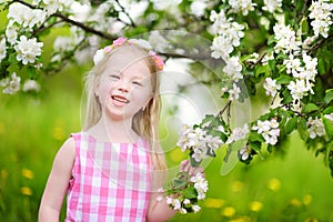 Adorable little girl in blooming apple tree garden on beautiful spring day