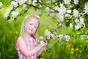 Adorable little girl in blooming apple tree garden on beautiful spring day