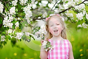 Adorable little girl in blooming apple tree garden on beautiful spring day