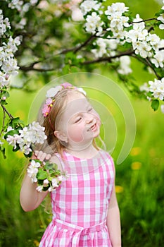 Adorable little girl in blooming apple tree garden on beautiful spring day