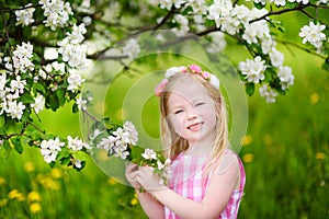 Adorable little girl in blooming apple tree garden on beautiful spring day