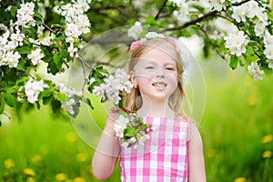 Adorable little girl in blooming apple tree garden on beautiful spring day