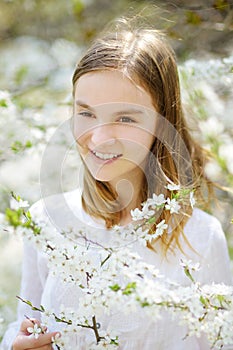 Adorable little girl in blooming apple tree garden on beautiful spring day