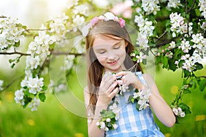 Adorable little girl in blooming apple tree garden on beautiful spring day