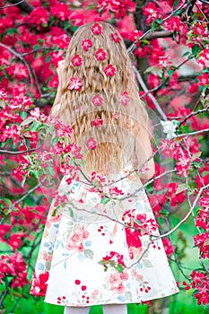 Adorable little girl in blooming apple tree garden on spring day