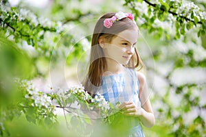 Adorable little girl in blooming apple tree garden on spring day