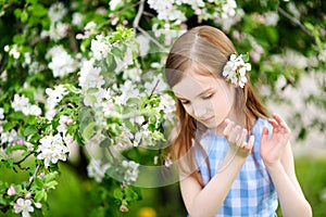 Adorable little girl in blooming apple tree garden on spring day