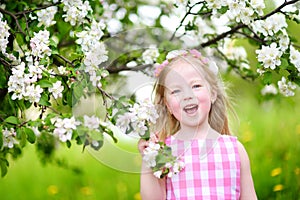 Adorable little girl in blooming apple tree garden on spring day