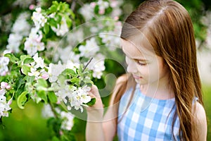 Adorable little girl in blooming apple tree garden on spring day