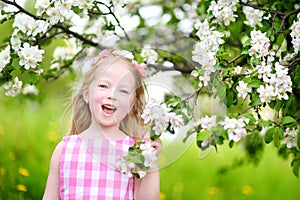 Adorable little girl in blooming apple tree garden on spring day