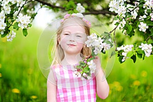 Adorable little girl in blooming apple tree garden on spring day