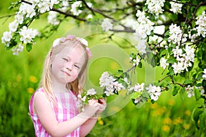 Adorable little girl in blooming apple tree garden on spring day