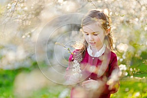 Adorable little girl in blooming cherry garden