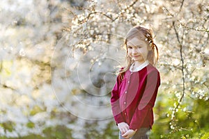 Adorable little girl in blooming cherry garden