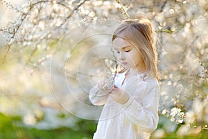 Adorable little girl in blooming cherry garden