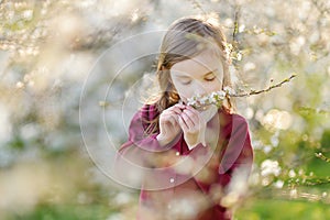 Adorable little girl in blooming cherry garden