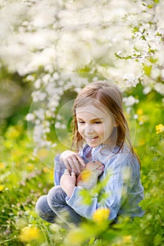 Adorable little girl in blooming cherry garden