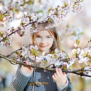 Adorable little girl in blooming cherry garden